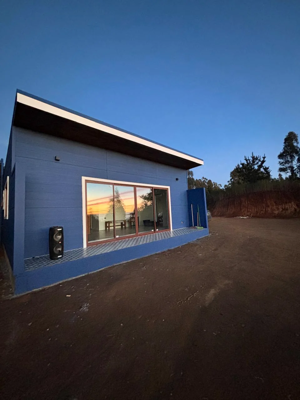Vivienda azul con ventanales amplios al atardecer