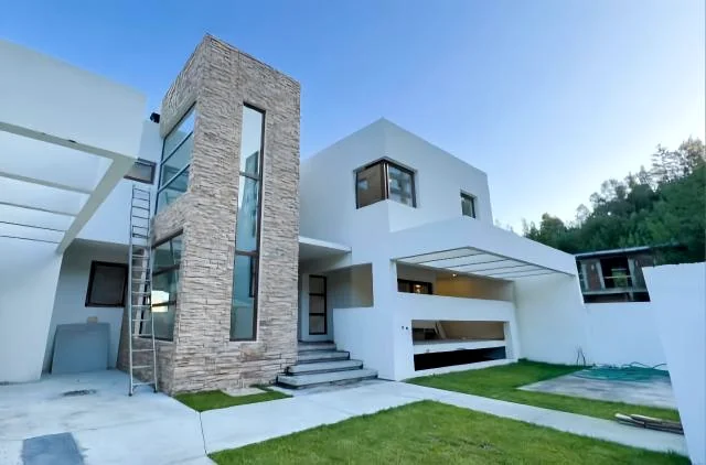 Vivienda contemporánea blanca con volumen revestido en piedra